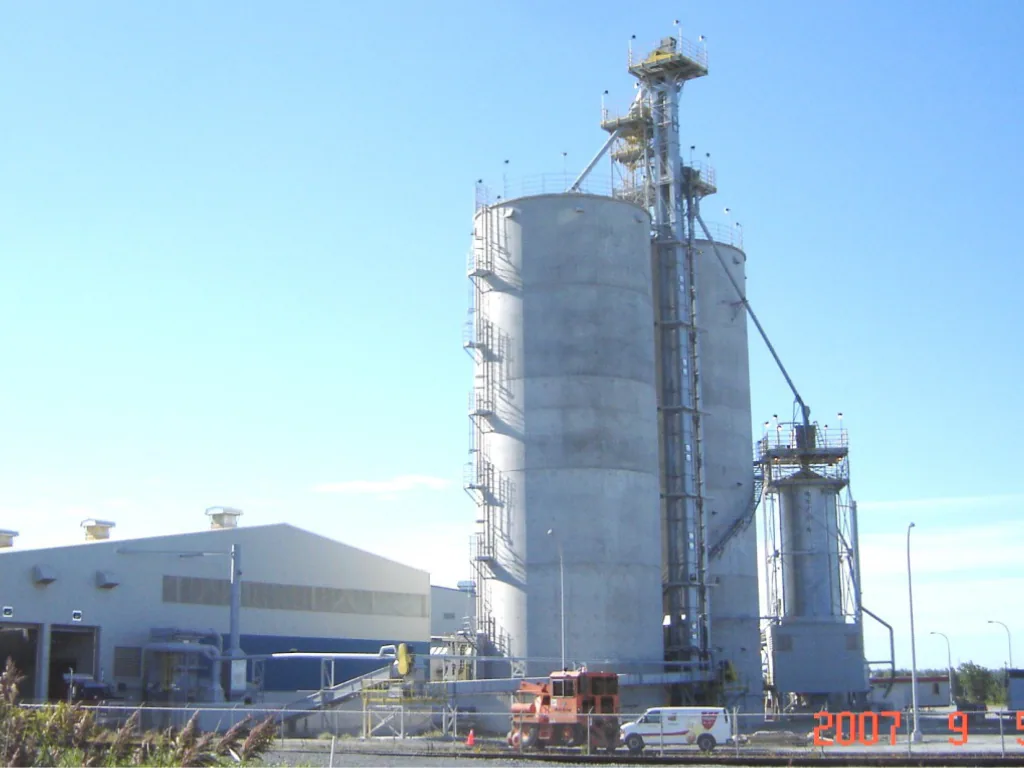 Silos and elevator tower at an ethanol plant, with industrial buildings in the foreground.