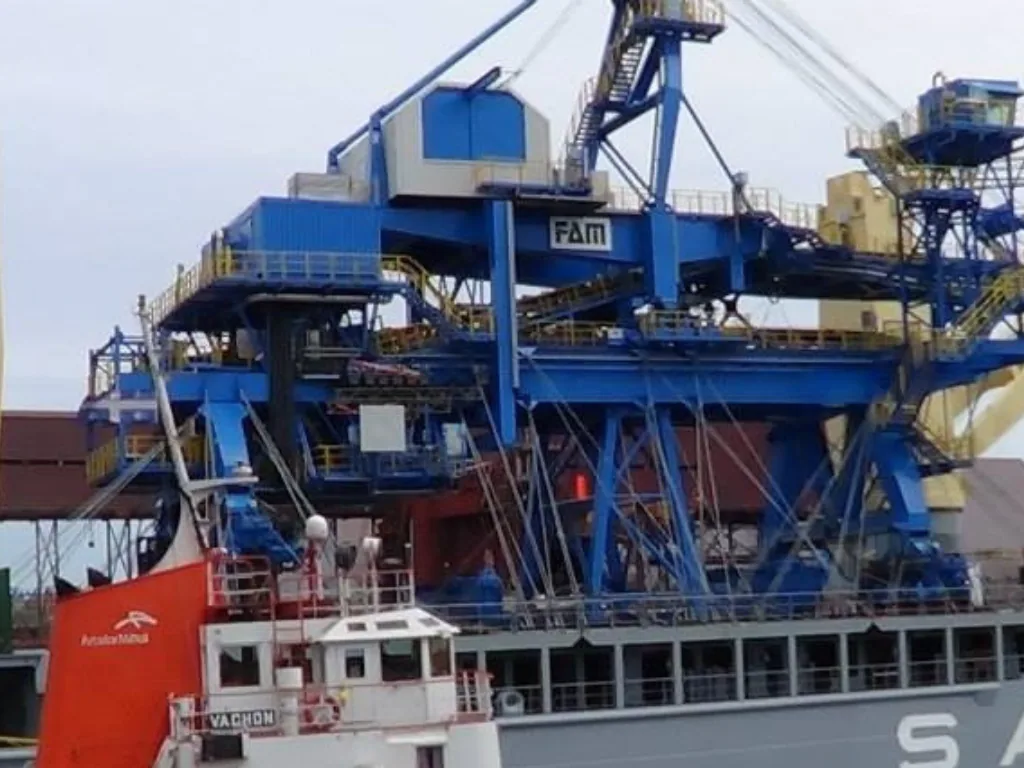 Blue industrial stacker-reclaimer and vessels alongside at Port-Cartier.