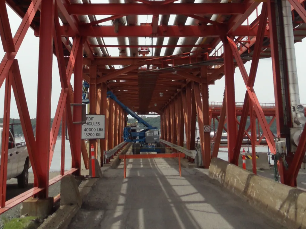Red steel structure enclosing a walkway and a large-diameter line at the Valero project site.