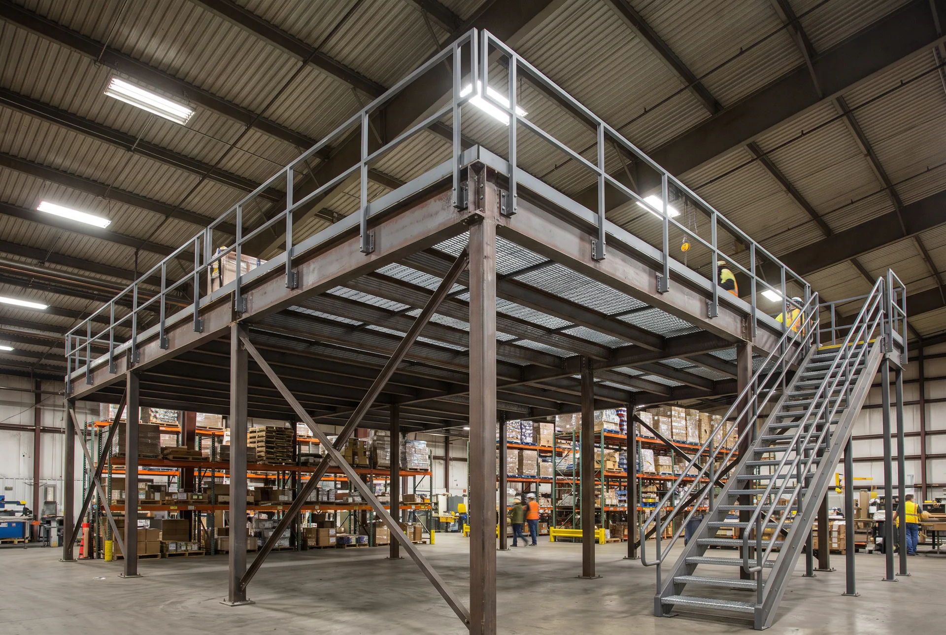 Generic bolted structural steel industrial mezzanine: platform on columns, guardrails and access stair, with no identifiable client or facility.